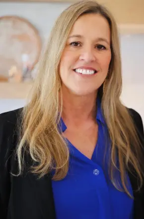 A woman with long blonde hair wearing a blue shirt.